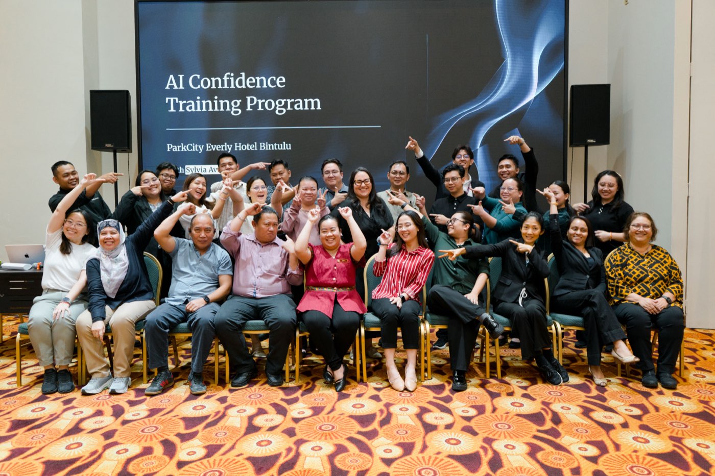 Workshop participants pointing at the AI Confidence Training Program screen with trainer Sylvia Avila in Bintulu, Malaysia